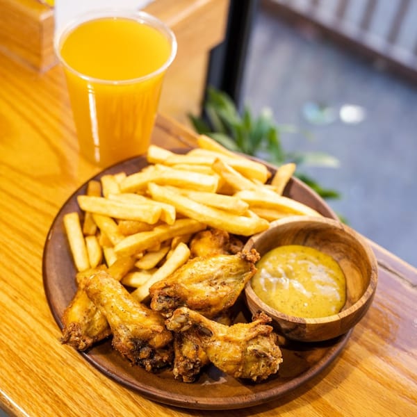 Blueline Fry's Haitian fried chicken wings, fries, and dipping sauce with a drink.