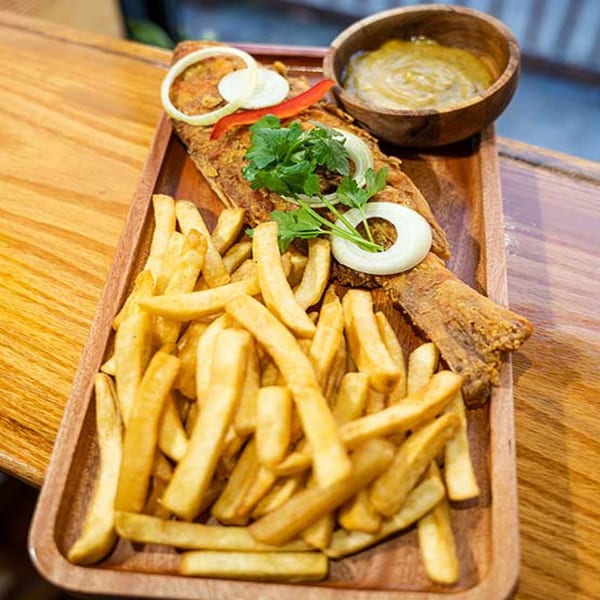 Haitian fried fish with onions, peppers, and parsley, served with fries and a dipping sauce.