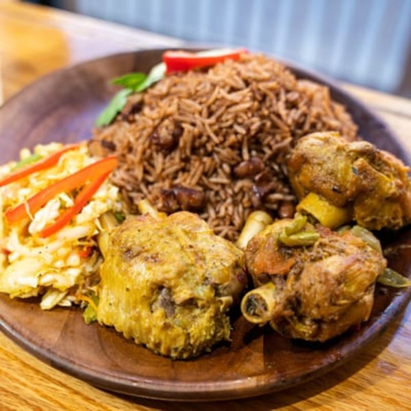 Haitian griot with rice and beans, and pikliz on a wooden plate.